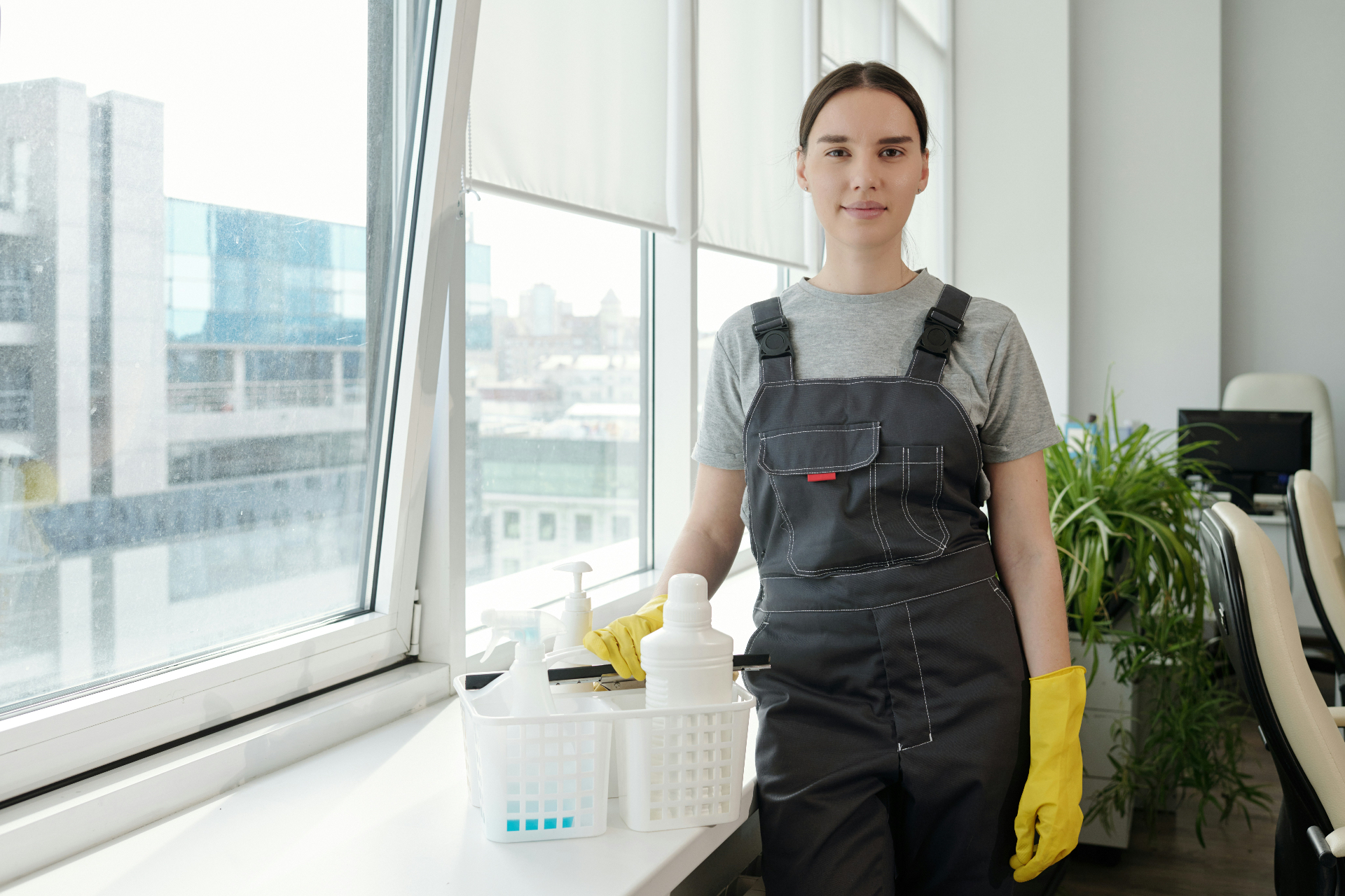 Cleaner standing by an office window with her supplies